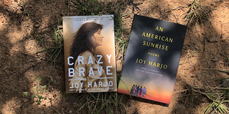 A photo of Crazy Brave and An American Sunrise by Joy Harjo in the dirt.