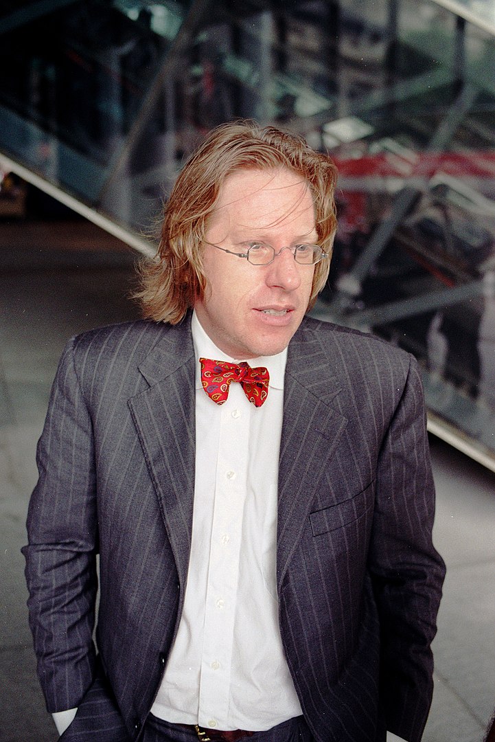 A photo of Jonathon Keats wearing a pinstripe suit with a red bowtie.